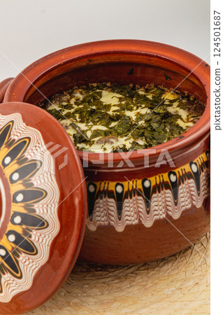Traditional clay pot filled with herbs and savory dish ready for serving 124501687