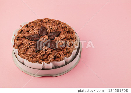 Chocolate cake decorated with cream and chocolate leaves on pink background 124501708
