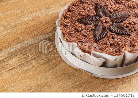Delicious round chocolate cake decorated with chocolate leaves on wooden table 124501712