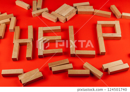 Wooden blocks spell out help on a red background 124501740
