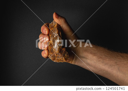 Strong hand gripping rough stone in a dark setting Strong hand gripping rough stone in a dark setting 124501741