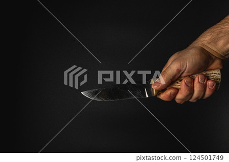 Holding a knife against a dark background Holding a knife against a dark background 124501749