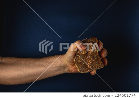 Strong hand holding a rock against dark background 124501774