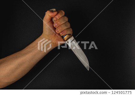 Strong hand gripping knife against dark background Strong hand gripping knife against dark background 124501775