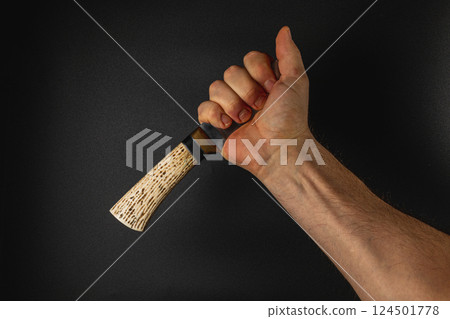 Hand gripping a handcrafted object against a dark backdrop 124501778