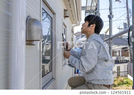 A man checking the progress of repair work on the exterior walls of a detached house A man checking the progress of repair work on the exterior walls of a detached house 124501911