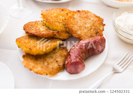 Potato pancakes with fried sausage on white plate 124502331