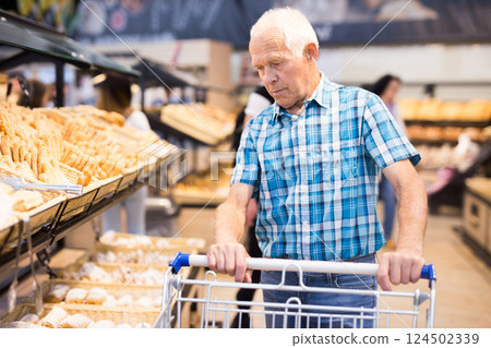 Elderly man buying bread and pastries in grocery section of the supermarket Elderly man buying bread and pastries in grocery section of the supermarket 124502339