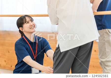 老年婦女使用扶手進行步行訓練，男女職能治療師和物理治療師工作人員協助她 124502381