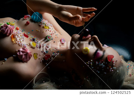 Woman adorned with body art and sweet treats in a creative beauty display Woman adorned with body art and sweet treats in a creative beauty display 124502525