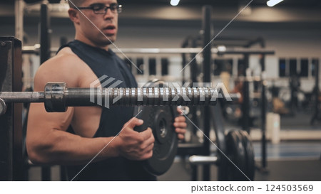 The male athlete arab changes the weight on the barbell. The male athlete arab changes the weight on the barbell. 124503569