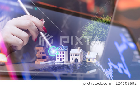 Close-up of a hand using a stylus over miniature houses, coins, and financial graphs, symbolizing real estate investment and online property market analysis. Close-up of a hand using a stylus over miniature houses, coins, and financial graphs, symbolizing real estate investment and online property market analysis. 124503692