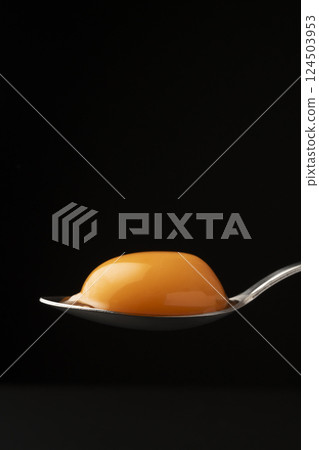 Egg yolk on a spoon on a black background 124503953