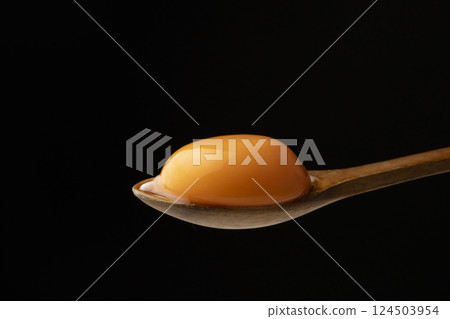 Egg yolk on a spoon on a black background 124503954