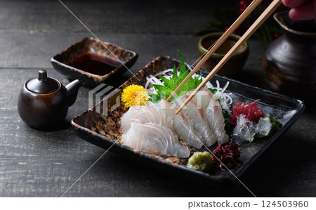 鯛魚刺身、白身刺身和日式餐具,用筷子夾起的優質食材 鯛魚刺身、白身刺身和日式餐具,用筷子夾起的優質食材 124503960