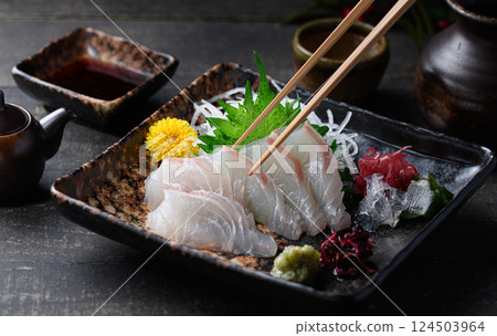 Sea bream sashimi, white fish sashimi and Japanese tableware, a high-quality piece picked up with chopsticks Sea bream sashimi, white fish sashimi and Japanese tableware, a high-quality piece picked up with chopsticks 124503964