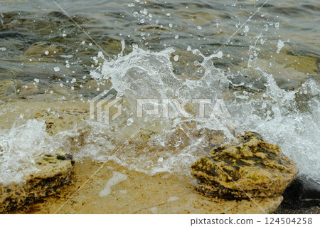 The Ocean Waves Are Splashing Vigorously on the Rocky Shoreline, Creating a Serene Atmosphere 124504258