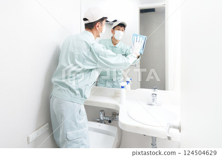 Male staff in work clothes cleaning the washroom 124504629