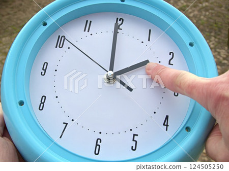 Hand adjusting the time on a clock 124505250
