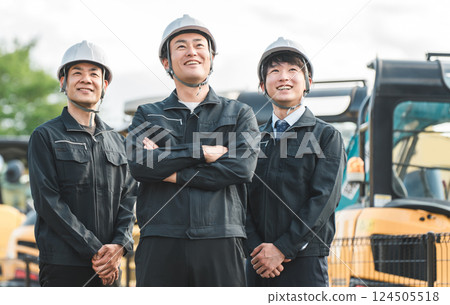 A male businessman working in the construction and building industry in work clothes in front of heavy machinery A male businessman working in the construction and building industry in work clothes in front of heavy machinery 124505518