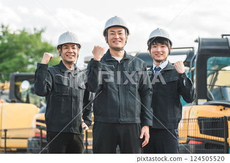 一名在建築業工作的男性商人，穿著工作服，站在重型機械前 124505520