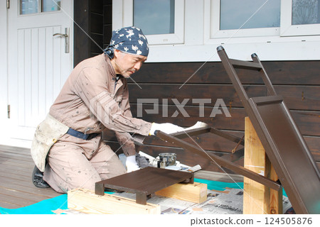 A middle-aged man painting a signboard 124505876