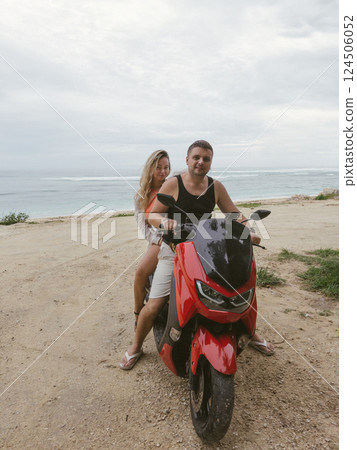 Young couple riding a scooter near the sea Young couple riding a scooter near the sea 124506052