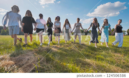 High school students linking arms and strolling through a summer field, relishing their friendship and independence 124506386