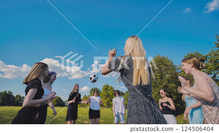 Friends toss a ball to each other in a meadow on a summer day. 124506404