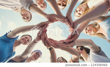 School friends join hands in a circle against a blue sky, representing unity, teamwork, and friendship School friends join hands in a circle against a blue sky, representing unity, teamwork, and friendship 124506468