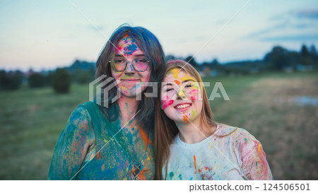 Two happy young women, covered in vibrant holi powder, embrace at a festival, celebrating friendship and the joy of color Two happy young women, covered in vibrant holi powder, embrace at a festival, celebrating friendship and the joy of color 124506501