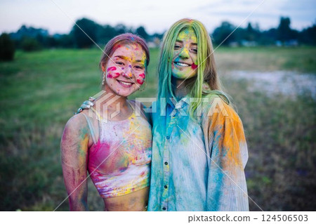 Two exuberant young ladies, adorned in vivid holi powder, enjoying the lively festivities outside with laughter and camaraderie Two exuberant young ladies, adorned in vivid holi powder, enjoying the lively festivities outside with laughter and camaraderie 124506503
