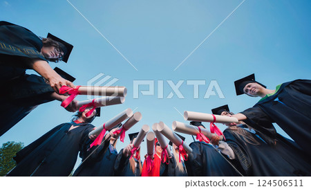 Students in a circle, proudly displaying their diplomas on graduation day 124506511