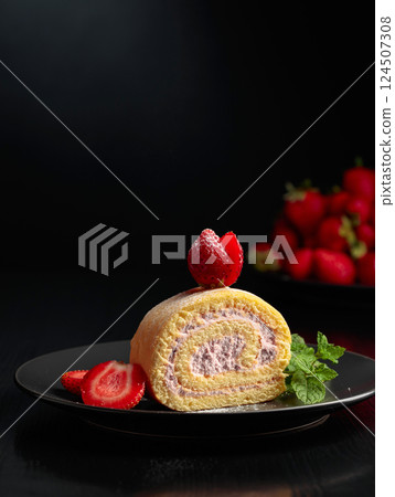 Delicious biscuit cake with strawberries on a black plate. 124507308