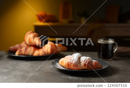 Fresh baked croissants and black coffee on a kitchen table. Fresh baked croissants and black coffee on a kitchen table. 124507310