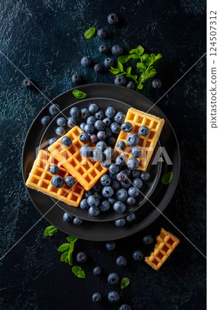 Belgian waffles with blueberries on a black plate. Belgian waffles with blueberries on a black plate. 124507312