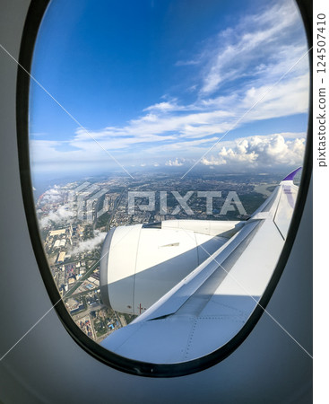 View from an airplane window showcasing a cityscape under a clear blue sky View from an airplane window showcasing a cityscape under a clear blue sky 124507410