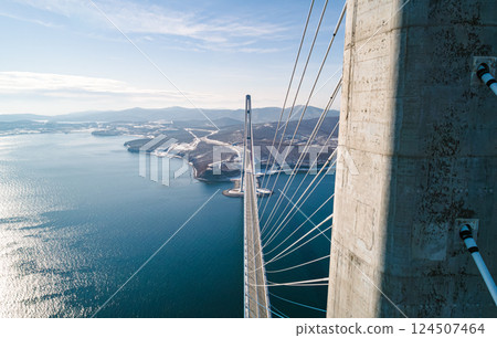Aerial view of the cable-stayed bridge in Vladivostok, highlighting its towering pillars and cables against a backdrop of clear skies and calm waters Aerial view of the cable-stayed bridge in Vladivostok, highlighting its towering pillars and cables against a backdrop of clear skies and calm waters 124507464