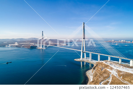 Stunning view of the Russky Bridge in Vladivostok with clear blue skies and tranquil waters. 124507465