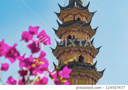 Colorful pagoda surrounded by vibrant flowers in sunlight captures serene beauty of the garden during daytime Colorful pagoda surrounded by vibrant flowers in sunlight captures serene beauty of the garden during daytime 124507477