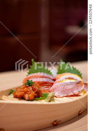 Salmon Sashimi set served on wooden sushi boat, with lemon and wasabi 124507648