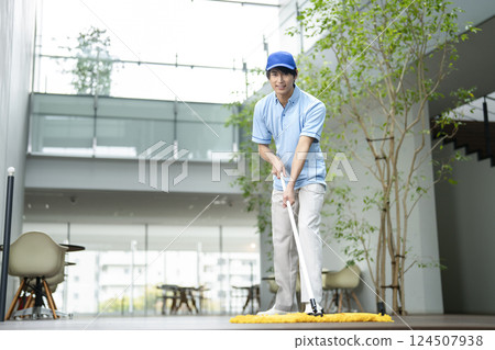 樓宇清潔圖片:男清潔人員拖地,看著相機 樓宇清潔圖片:男清潔人員拖地,看著相機 124507938