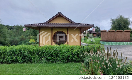 Traditional Japanese garden pavilion surrounded by lush greenery and trees with sunlight filtering through. Zen and tranquility concept for design and print 124508185
