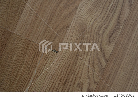 Laminate flooring with visible defects like chips, cracks, and unevenness. 124508302