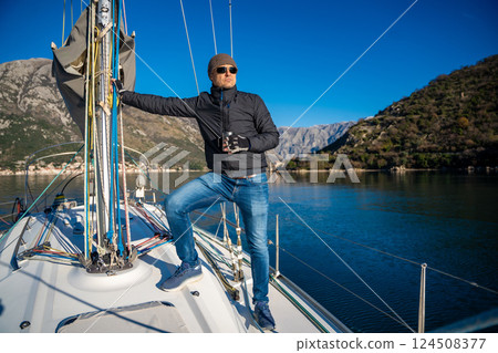 Man holding thermo mug on bow of the yacht during sailing in the morning in winter time in Adriatic sea, relaxation in yachting time 124508377