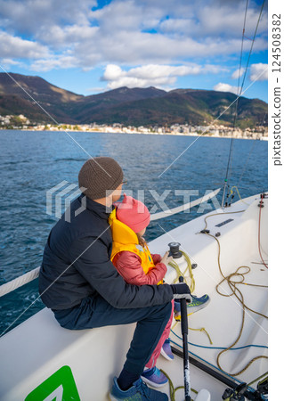 Father instructing daughter on sailing a yacht during training in the Kotor Bay, Montenegro, highlighting family bonding, adventure, and nautical sport. Father instructing daughter on sailing a yacht during training in the Kotor Bay, Montenegro, highlighting family bonding, adventure, and nautical sport. 124508382