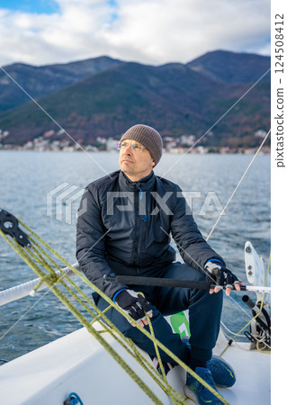 Man sailing a sports yacht in the Kotor Bay, Montenegro, showcasing adventure, freedom, and nautical sport. Man sailing a sports yacht in the Kotor Bay, Montenegro, showcasing adventure, freedom, and nautical sport. 124508412