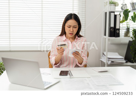 Financial Stress and Management. A woman looks confused while handling credit cards and bills in her home office. Financial Stress and Management. A woman looks confused while handling credit cards and bills in her home office. 124509233