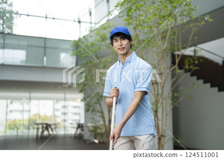 Smiling young male cleaning staff looking at camera 124511001