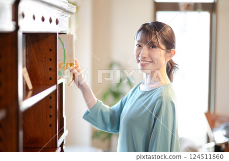 A woman picking up a book from a bookshelf 124511860